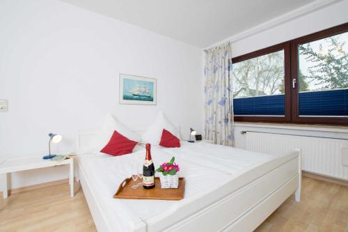 Schlafzimmer mit einem weißen Bett und einer Flasche Wein in der Unterkunft MEI77 Ferienwohnung Zimmermann F in Niendorf