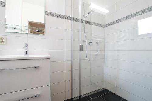 ein weißes Bad mit einer Dusche und einem Waschbecken in der Unterkunft MEI77 Ferienwohnung Zimmermann F in Niendorf
