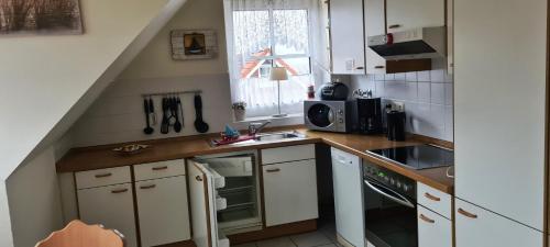 een kleine keuken met witte kasten en een wastafel bij OST29 Ferienwohnung Komoran in Niendorf