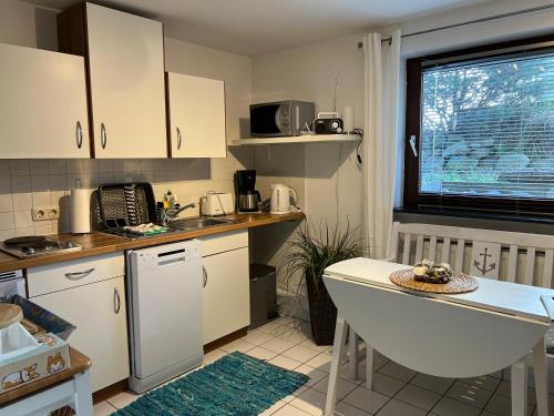 uma cozinha com armários brancos, um lavatório e uma mesa em STOE12c Ferienhaus Sonne, Wohnung Sonnenschein em Niendorf