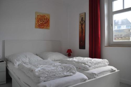 2 weiße Betten in einem Zimmer mit Fenster in der Unterkunft STR123L Ferienwohnung Sarah in Niendorf