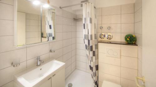ein weißes Bad mit einem Waschbecken und einer Dusche in der Unterkunft STR123L Ferienwohnung Sarah in Niendorf