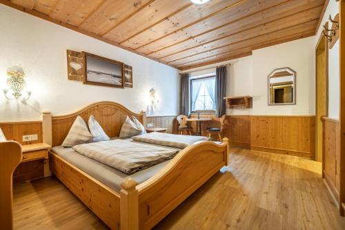 a bedroom with a wooden bed and a desk at Das Geierberg in Filzmoos