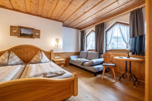 a bedroom with a bed and a couch and a tv at Das Geierberg in Filzmoos