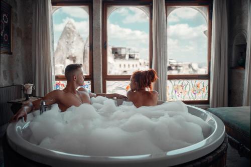 a man and woman sitting in a bathtub filled with foam at Sultan Cave Suites in Göreme
