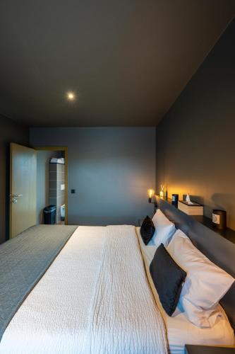a bedroom with a large white bed with two pillows at M-otel E40 in Wetteren
