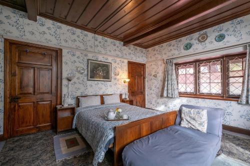 a bedroom with a bed and a table and a chair at StayVista at Northwood Cottage with Vintage Luxury in Shimla