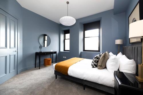 Dormitorio azul con cama y escritorio en ALTIDO Luxury 2BR home on George Street, en Edimburgo