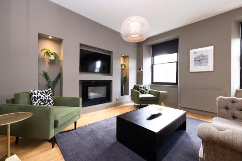 sala de estar con muebles verdes y chimenea en ALTIDO Luxury 2BR home on George Street, en Edimburgo