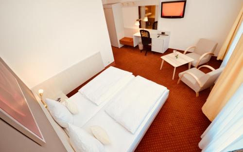 a hotel room with a white bed and a desk at CityHotel Uelzen in Uelzen