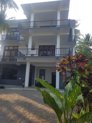 a large white building with a balcony and a plant at Waves Hiri Sea View in Hiriketiya