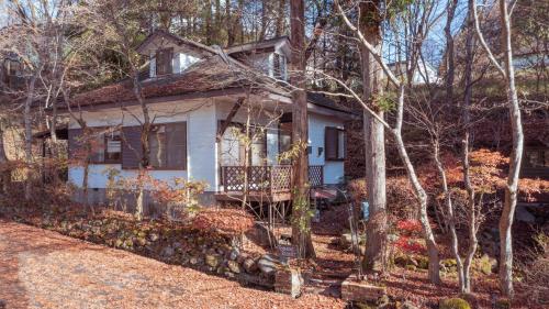 a white house with a porch in the woods at TOSHINO RESORT Nikko in Nikko