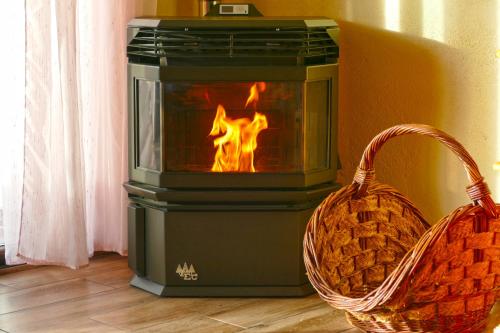 a stove with a fire in it next to a basket at El Triskel de Chumbea, alojamiento excepcional con maravillosas vistas a 5km de Béjar in Navalmoral de Béjar