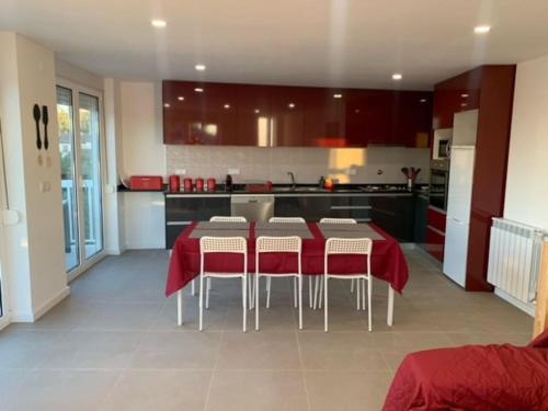 uma cozinha com uma mesa vermelha e cadeiras numa cozinha em Cantinho de Vale Maior em Penacova