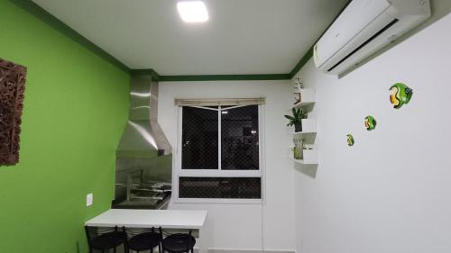 a kitchen with green walls and a white table and chairs at Apartamento Resort Palmeiras 2 com 03 Quartos Ubatuba in Ubatuba