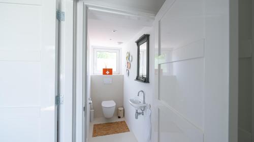 a white bathroom with a toilet and a mirror at gastenverblijf Pure Rust in Wouterswoude