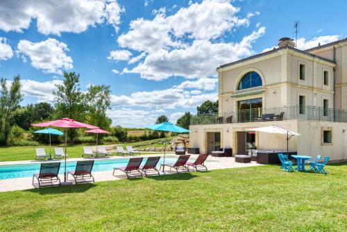 une piscine avec chaises et parasols devant un immeuble dans l'établissement Château La Poste, à Petit-Palais-et-Cornemps