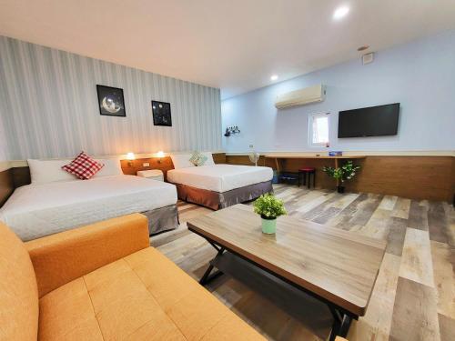 a hotel room with two beds and a couch and a tv at Xing Ji Bungalow in Kenting