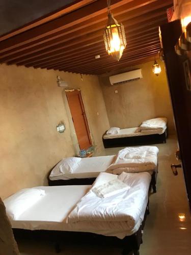 a room with three beds and a chandelier at Hissen Al-Misfah in Misfāh