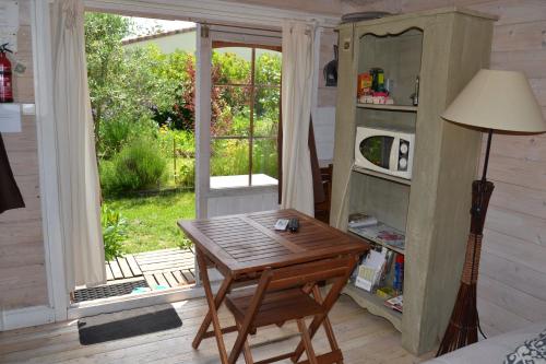 Habitación con mesa de madera y ventana. en Le chalet du Jardin caché, en Marmande