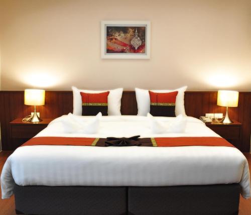 a large bed in a hotel room with two lamps at Avion Hotel in Lat Krabang