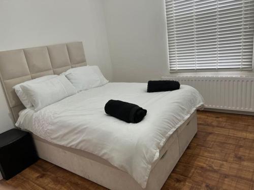 a white bed with two black pillows on it at Lovely 1-Bedroom Home With Free Parking & Garden. in London