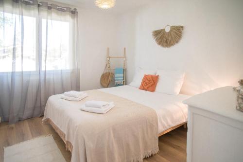 a white bedroom with a bed with towels on it at Villa Nina- Maison cocon cosy in La Teste-de-Buch