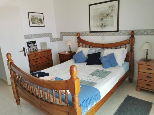 Un dormitorio con una gran cama de madera con almohadas azules en MEDITERRANEAN VALLEY, en Pafos