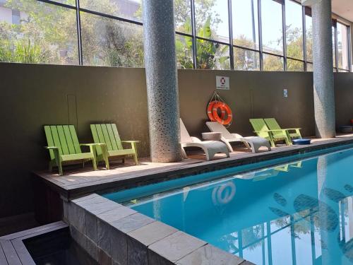 a swimming pool with green chairs and chairs next to a building at Urban Park Private Apartment in Durban