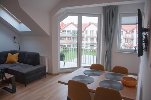 a living room with a table and a couch at Apartament BURSZTYN in Darłówko