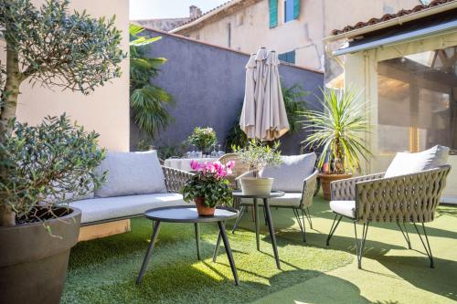 a patio with a couch and chairs and an umbrella at Logis Hôtel La Fenière in La Bouilladisse