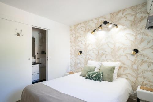 a bedroom with a white bed and a wall at Logis Hôtel La Fenière in La Bouilladisse