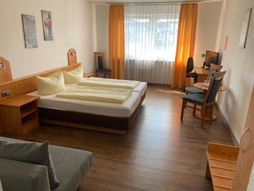 een slaapkamer met een bed, een stoel en een bank bij Hotel Sonne - Haus 1 in Idstein