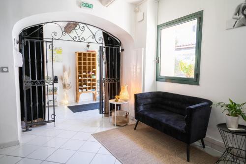 a living room with a black couch and a window at Logis Hôtel La Fenière in La Bouilladisse