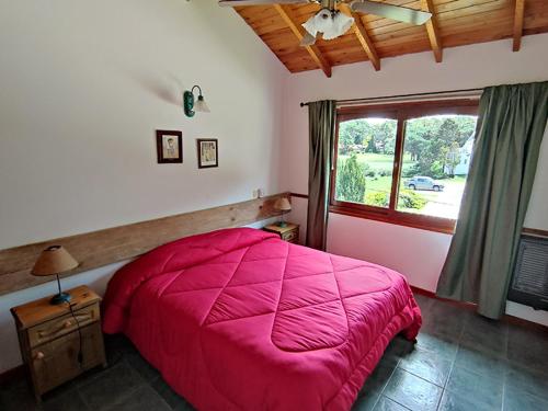 1 dormitorio con cama rosa y ventana en Complejo Frente al Golf, en Pinamar