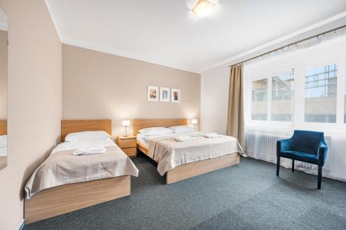 um quarto com 2 camas e uma cadeira azul em Pension Petit em Bratislava