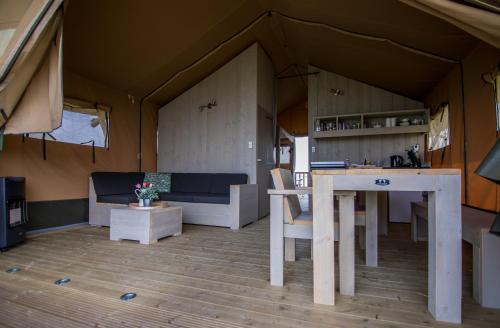 a living room with a table and a kitchen in a tent at Jachthaven Nieuwboer in Bunschoten