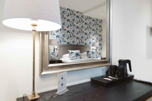 um quarto com um espelho e uma mesa com um candeeiro em Hotel Bastian em Helsinque