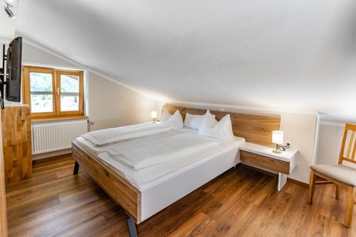 a bedroom with a large white bed and a chair at Gästehaus Hinterponholz in Ramsau