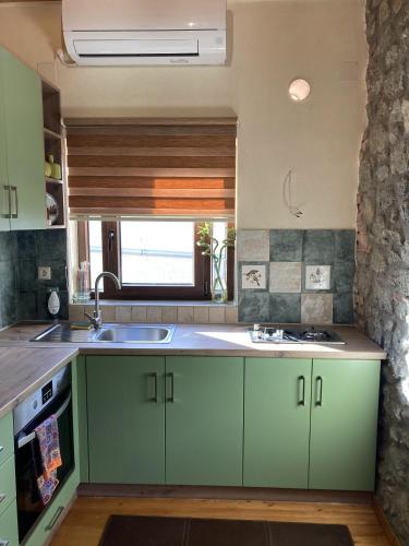 a kitchen with green cabinets and a sink at Meraki in Kalabaka