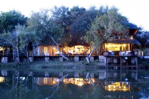 a house sitting on the shore of a body of water at Mogalakwena River Lodge in Alldays