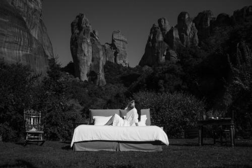 a woman sitting on a bed in a field at Pyrgos Adrachti in Kalabaka