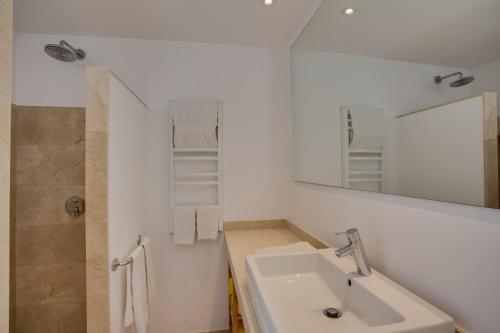 ein weißes Badezimmer mit einem Waschbecken und einem Spiegel in der Unterkunft Ideal Property Mallorca - Padri in Font de Sa Cala