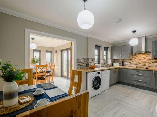 an open kitchen and dining room with a table and a washer at Westertonhill Lodge - 3 Double Bedrooms Sleeps 8 With Private Hot Tub Hire Available in Balloch