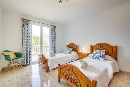 プラヤ・デ・ムロにあるVilla Corb Mariのベッドルーム1室(ベッド2台、椅子、窓付)