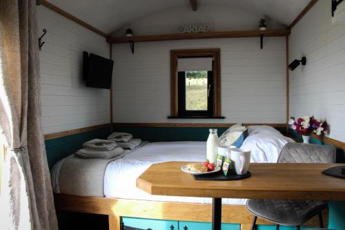 a small bedroom with a bed and a table at Cwm Cariad in Knighton