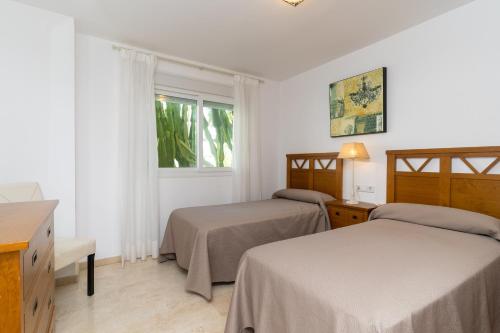 a hotel room with two beds and a window at Guadalmina Baja in Marbella