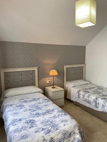 1 dormitorio con 2 camas y mesita de noche con lámpara en Torneo Atico Premium Apartment, en Sevilla
