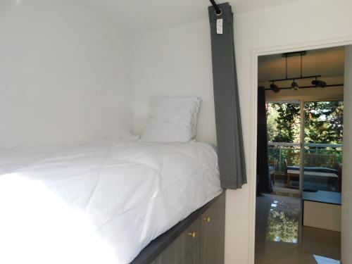 ein Schlafzimmer mit einem weißen Bett und einer Glasschiebetür in der Unterkunft Studio résidence Golfe Marine avec piscine et parking in Vallauris