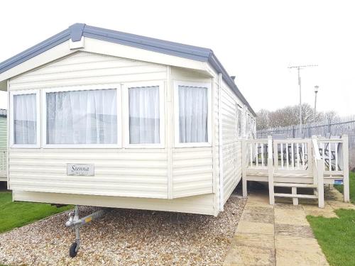 a white shed with a porch and a bench at BUTLINS SKEGNESS, 3 Beds, Pet Friendly - The Paddock in Lincolnshire